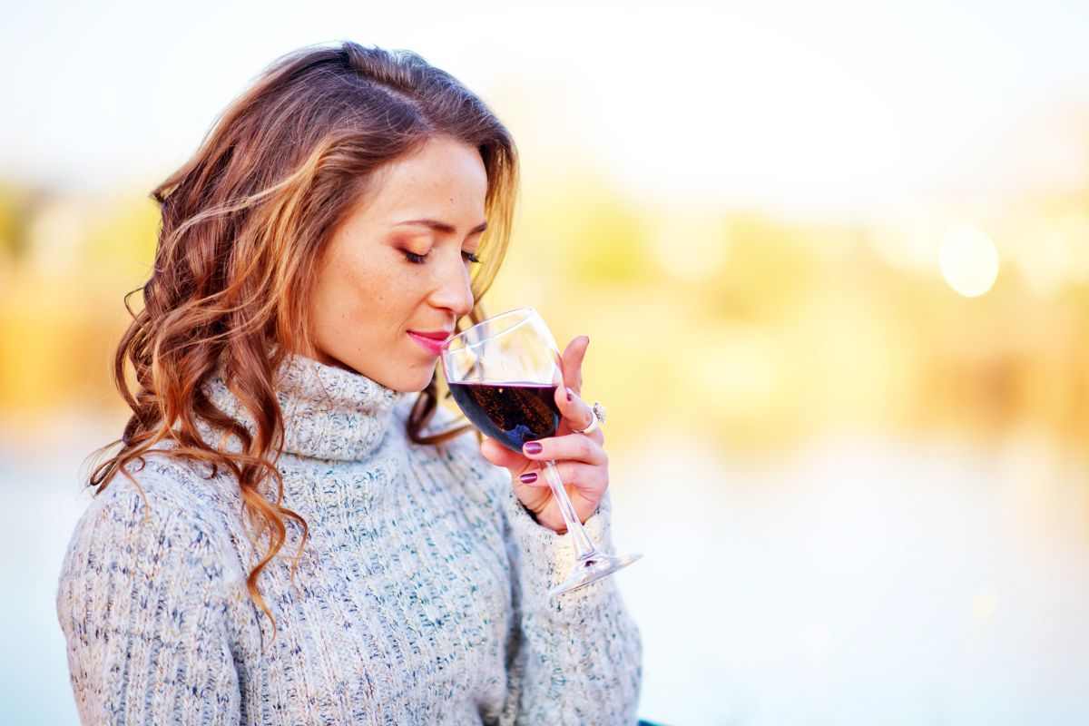 Donna beve calice di vino rosso