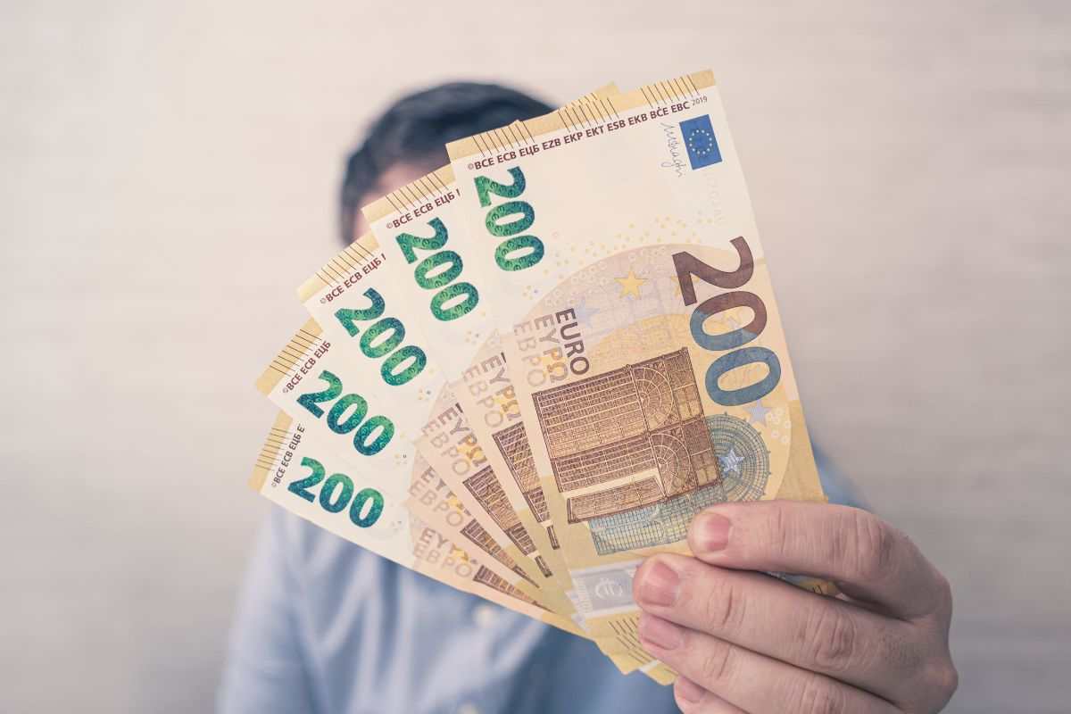 uomo con in mano 5 banconote da 200 euro