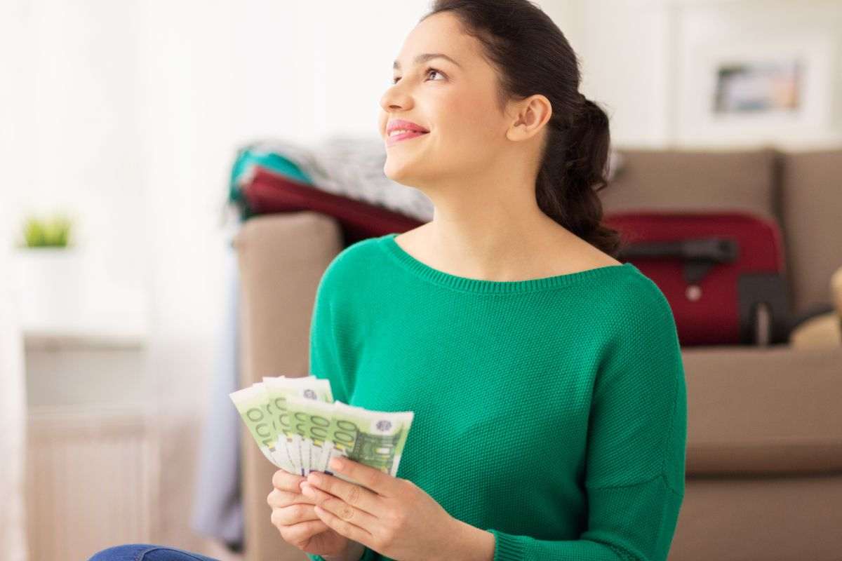 donna con in mano banconote da 100 euro che pensa a cosa farci