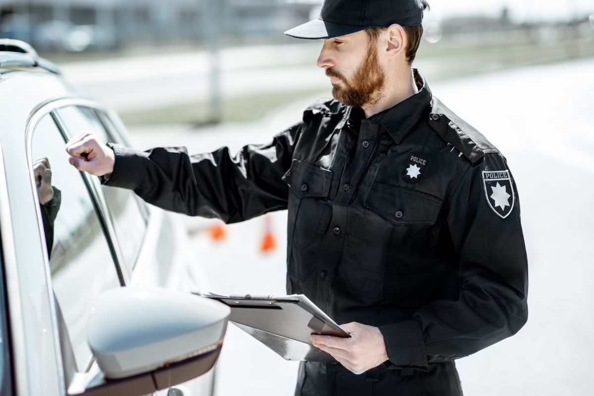 poliziotto che bussa sul finestrino di un'auto